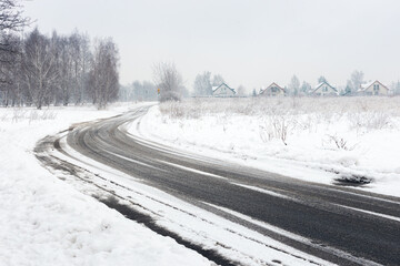 Curved Snowy Road in Rural Winter Landscape with melting snow or black Ice