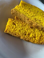 Homemade slice of yellow sponge cake on white plate, sweet dessert