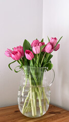 pink tulips in a transparent vase on table