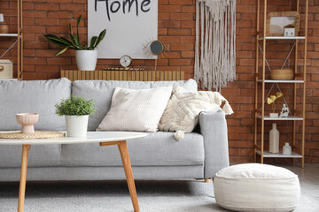 Comfortable sofa and coffee table with houseplant in interior of living room
