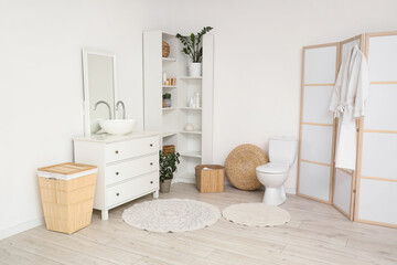 Interior of light restroom with sink, shelf unit and toilet bowl