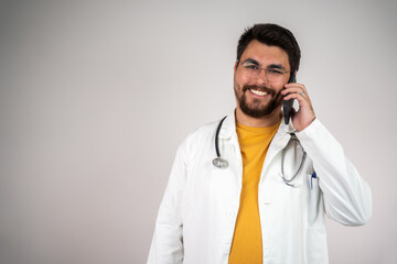 Smiling doctor talking on mobile phone, professional healthcare provider using smartphone in medical setting, confident physician in casual attire, communication with patient or colleague.