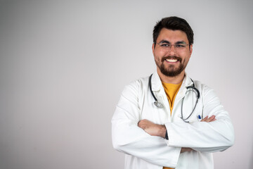 Fototapeta premium Male doctor portrait. Medium shot of handsome doctor standing with crossed arms. Isolated. Confident doctor at the isolated on grey wall background.