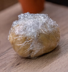 Dough pastry made from flour, eggs and butter in food wrap prepared to make a quiche