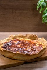 A quiche with fried smoked bacon and cheese in a pie pan on table. Copy space.