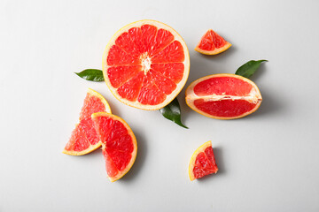 Cut fresh grapefruit and leaves on grey background