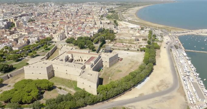 Aerial view of the castle located in Barletta, Puglia, Italy. It was a medieval fortress. In background is the Basilica of Santa Maria Maggiore, cathedral of the city, and the Mediterranean sea.