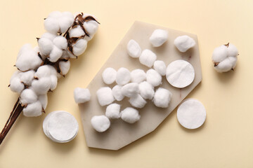 Board with cotton balls, pads and flowers on beige background