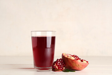 Glass of fresh pomegranate juice on white wooden table
