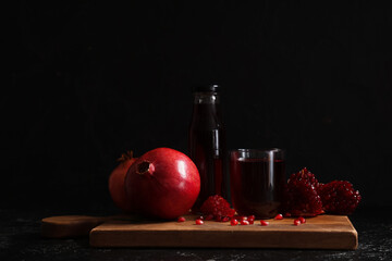 Glass and bottle of fresh pomegranate juice on black background