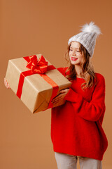 Young girl in red sweater and warm hat poses with gift boxes