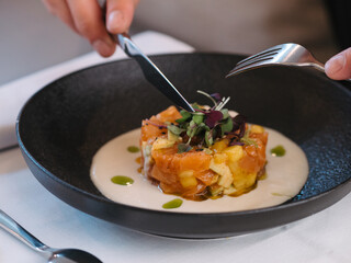 a man eating a plate of salmon tartare in a restaurant