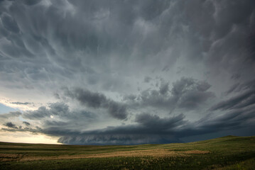 An ominous storm spins over the sandhills in western Nebraska as puffy mammatus clouds droop overhead.