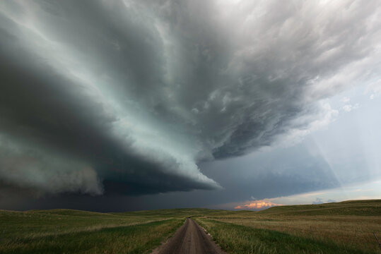 A powerful storm rolls over the Sandhills of western Nebraska with a single dirt road going off into the distance.