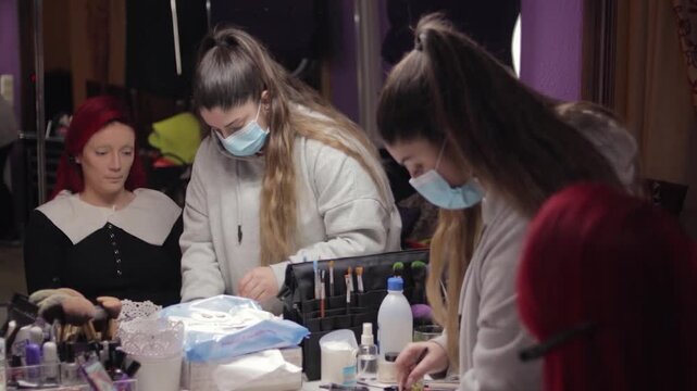 Makeup Artist Applying Character Makeup to Redhead Woman &ndash; Mid Shot Reflected in Mirror. Maquilladora Aplicando Maquillaje de Caracterizaci&oacute;n a Mujer Pelirroja &ndash; Plano Medio Reflejado en el Espejo
