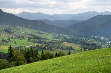 Mountain landscape with village and a green pasture in the foreground.