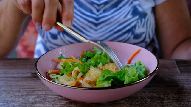 Senior woman in the cafe, eating healthy Spicy Tremella Mushroom Salad with squid, carrot , lettuce