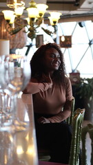 Confident successful young African American woman relaxing at the bar counter of a restaurant