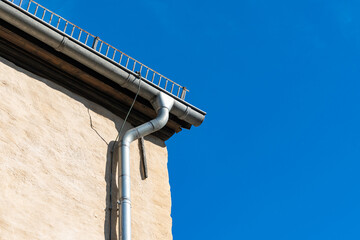 A close-up of the corner roof and roof gutter on an old building. © Viktor