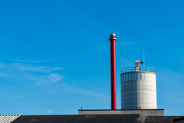 Industrial chimney and smoke stack against clear blue sky