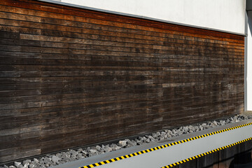 Wooden wall with weathered texture beside a stone pathway in daylight