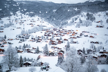 Grindelwald, under the soft glow of the night lights, transforms into a magical village where the snow glistens and each chalet seems to watch over the peaceful, slumbering mountains, Switzerland.