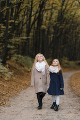 Fototapeta premium two girls with fair hair take a walk in the autumn park