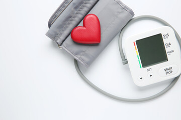 Blood pressure measuring device and heart figure on white background, top view. Space for text
