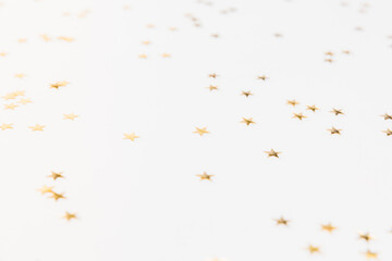 Gold sparkle confetti stars on a white background. Glitter, shine, bright. Christmas festive flat lay, winter holiday, new year, happy birthday concept. Flat lay, top view, copy space.