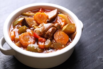 Delicious stew with vegetables in bowl on gray textured table, closeup