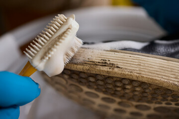 The process of cleaning shoes is currently underway, utilizing a foam and a brush diligently