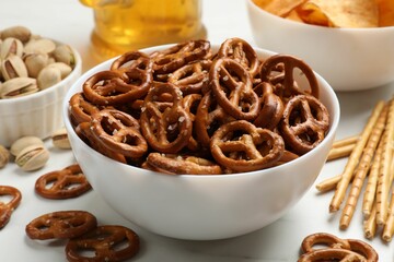 Delicious pretzel crackers and other snacks on white table, closeup