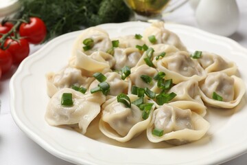 Delicious pelmeni with green onion on white table, closeup