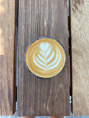 Cup of coffee with latte art design on wooden background