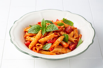Classic italian pasta penne alla arrabiata with basil and freshly grated parmesan cheese on dark table. Penne pasta with chili sauce arrabbiata.
