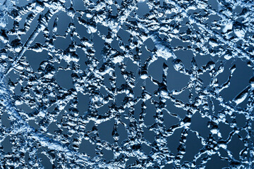 Blue water texture with bubbles. Liquid drops and light reflections. Cold winter background with icy, wet details. Nature-inspired wallpaper design. Frozen water structure. Ice net texture.