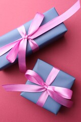 Beautiful gift boxes with bows on pink background, top view