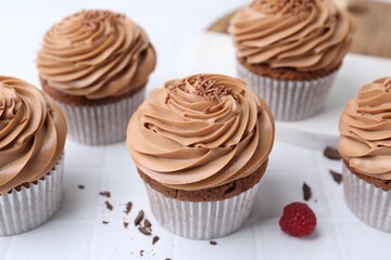 Tasty cupcakes with chocolate cream on white tiled table, closeup