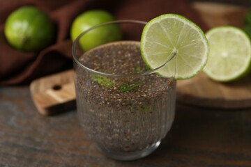 Glass of drink with chia seeds and lime on wooden table, closeup