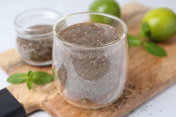 Glass of drink with chia seeds and lime on white table, closeup