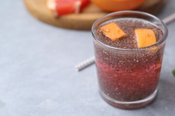 Glass of drink with chia seeds and grapefruit on grey table, closeup. Space for text