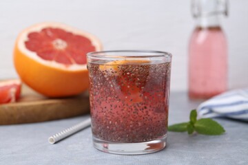 Glass of drink with chia seeds and grapefruit on grey table, closeup