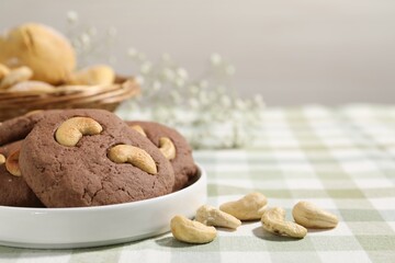 Tasty chocolate cookies with cashew on table, closeup. Space for text
