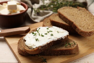 Fresh bread with butter, thyme and knife on light table, closeup