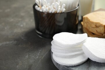 Many cotton pads and swabs on grey textured table, closeup. Space for text