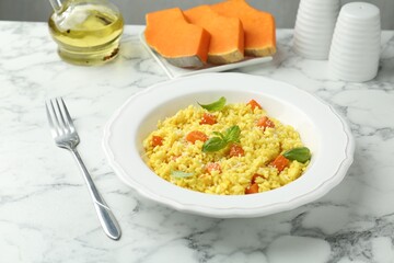 Delicious pumpkin risotto served on white marble table, closeup