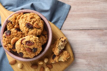 Delicious oatmeal cookies with raisins and nuts on wooden table, top view. Space for text
