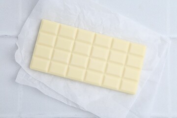 Delicious white chocolate bar on tiled table, top view