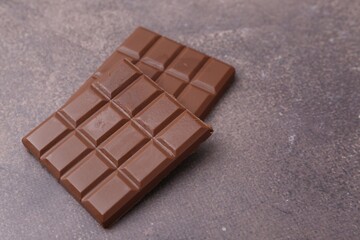 Pieces of delicious milk chocolate on brown table, closeup. Space for text