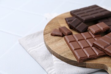Different types of chocolate on white tiled table, closeup. Space for text
